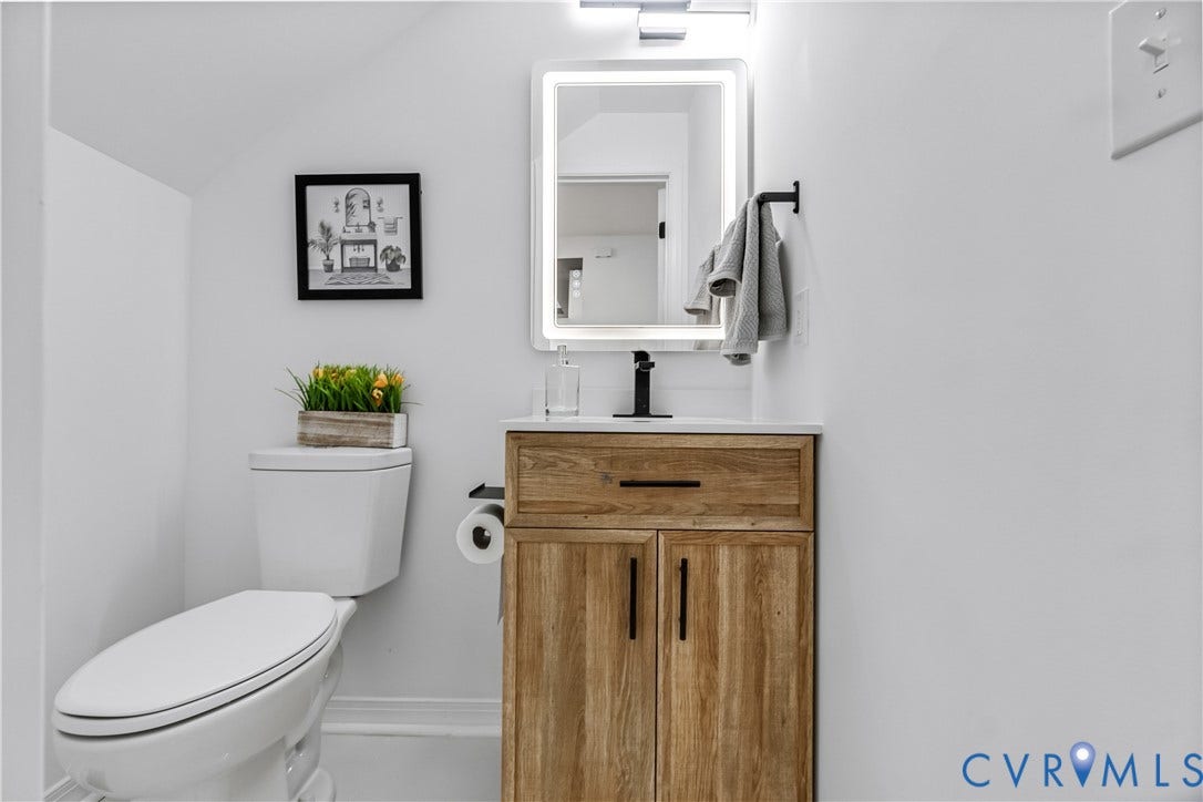 223 S Crater Road, Petersburg, VA 23803 Wood-finish vanity with a rectangular sink, matte black hardware, integrated light-up mirror, and minimalist faucet