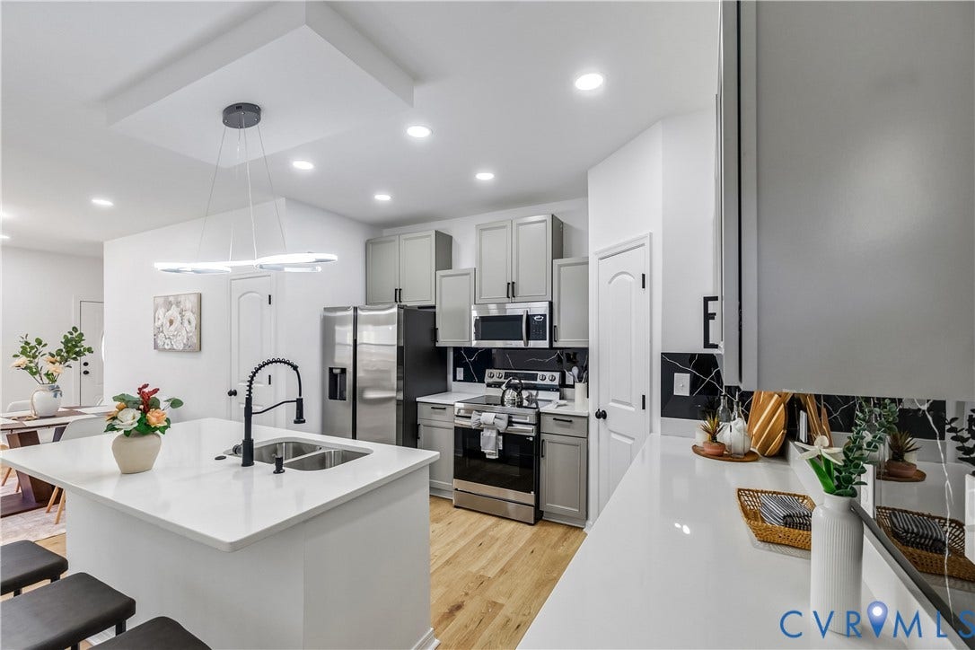 223 S Crater Road, Petersburg, VA 23803 Kitchen featuring an expansive central island with a dual-basin undermount sink, quartz countertops, gray shaker-style cabinetry, stainless steel appliances, and wood-finish flooring