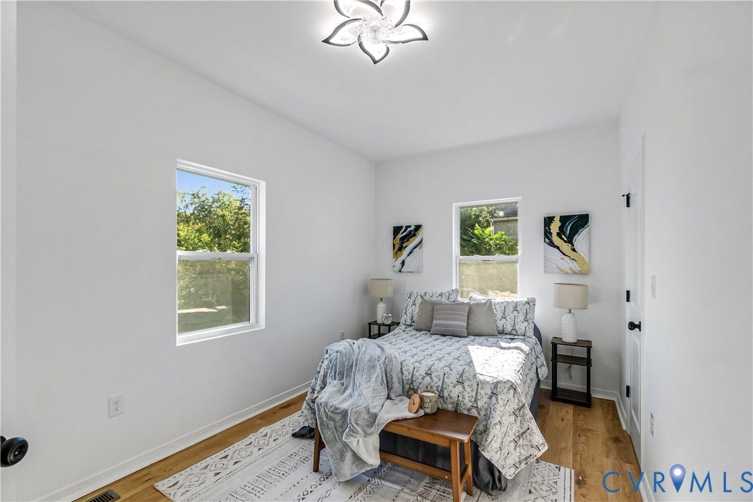 223 S Crater Road, Petersburg, VA 23803 Room featuring wood-finish flooring, two double-pane windows, and a decorative floral-inspired ceiling fixture