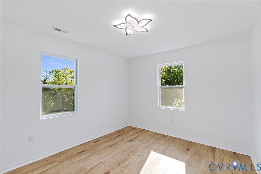 223 S Crater Road, Petersburg, VA 23803 Bright room featuring light wood-finish flooring, two large windows, and a decorative floral-inspired ceiling fixture