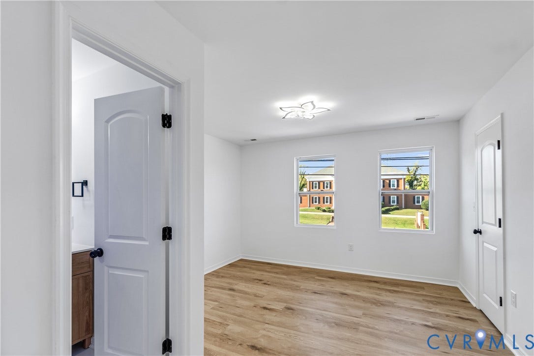 223 S Crater Road, Petersburg, VA 23803 Interior room featuring wood-finish flooring, two double-hung windows, white arched-panel doors, and a contemporary floral-style flush-mount ceiling light