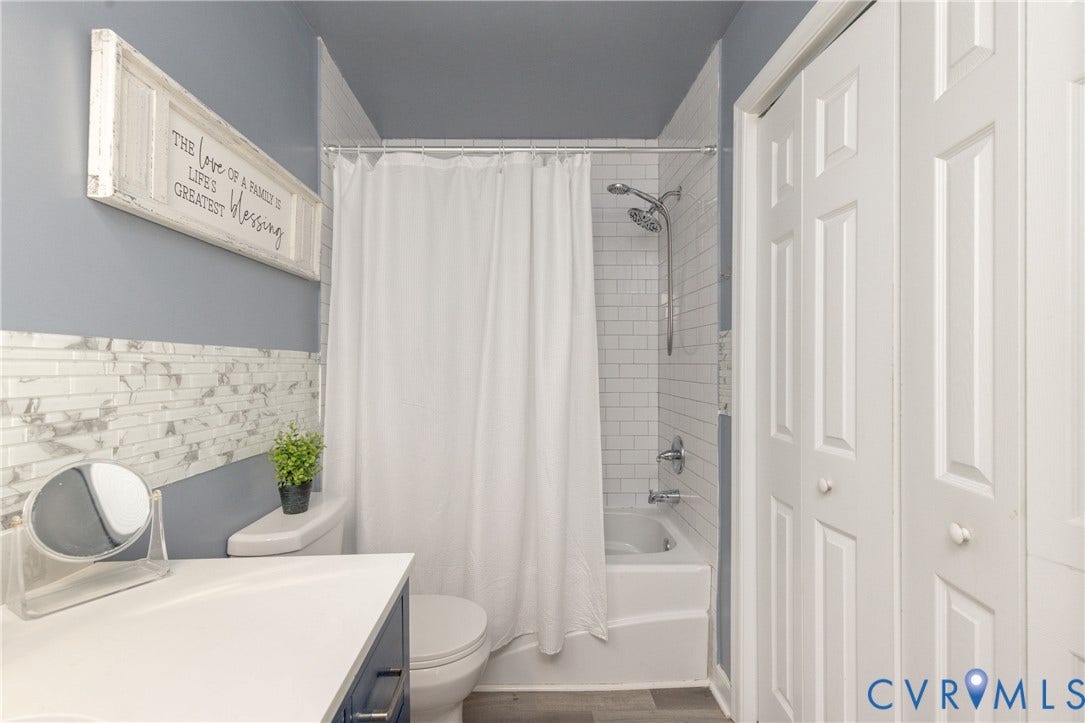 3705 Yard Arm Drive, Chesterfield, VA 23831 Bathroom featuring a tub-shower combination with white subway tile surround, decorative stone-finish tile accent, dual-panel bifold closet doors, and wood-finish flooring