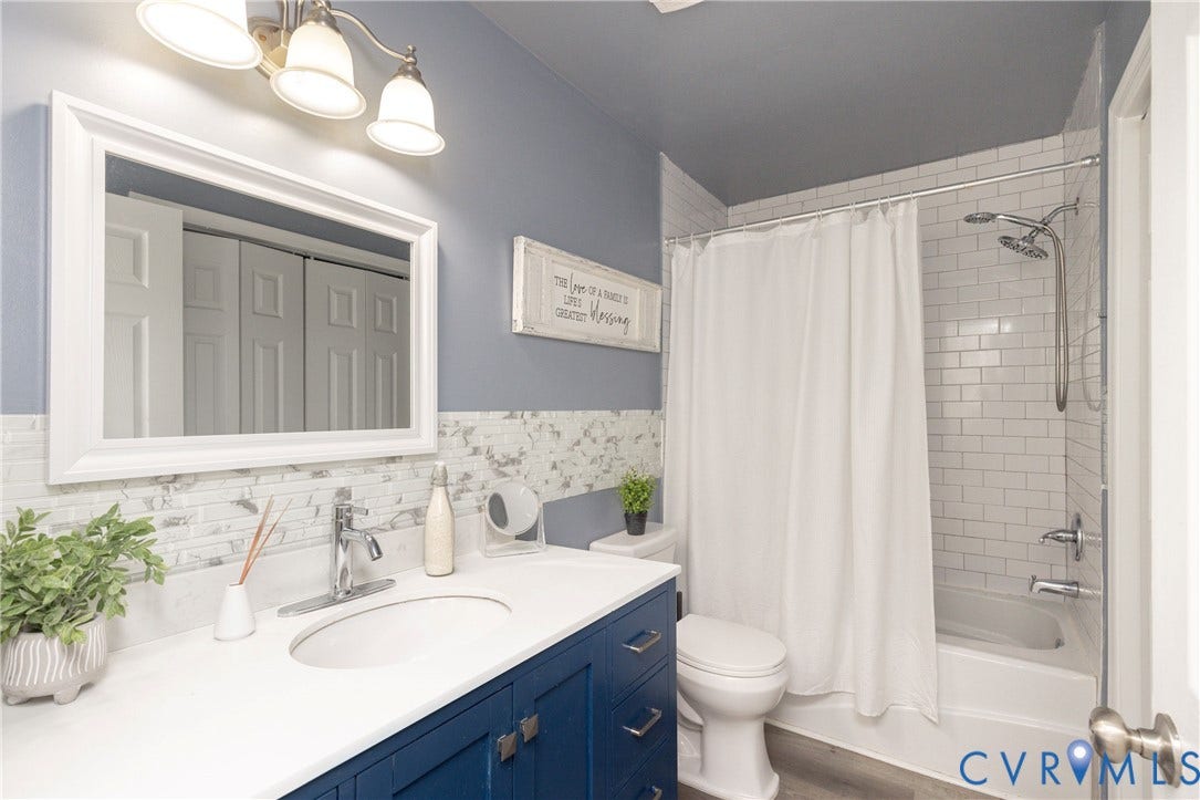 3705 Yard Arm Drive, Chesterfield, VA 23831 Bathroom featuring a vanity with white countertop and integrated sink, subway-tiled shower surround, three-light wall fixture, framed mirror, and chrome finish hardware