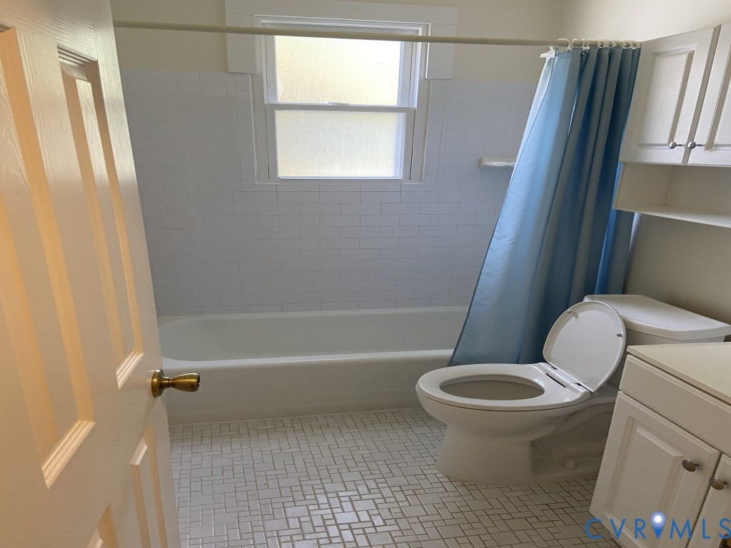 8358 Patrick Henry Boulevard, Mechanicsville, VA 23116 Bathroom featuring white subway tile tub surround, basketweave patterned tile flooring, built-in cabinetry, and a double-hung window