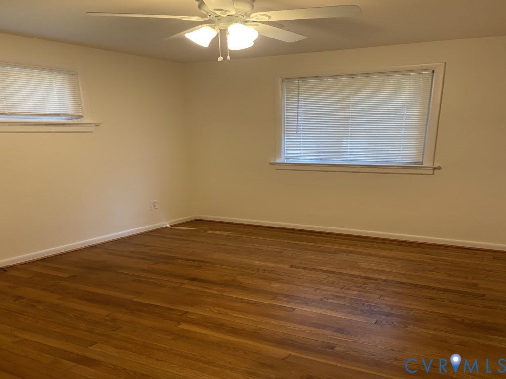 8358 Patrick Henry Boulevard, Mechanicsville, VA 23116 Room featuring wood-finish flooring, neutral wall paint, two windows with horizontal blinds, and a ceiling-mounted light fixture