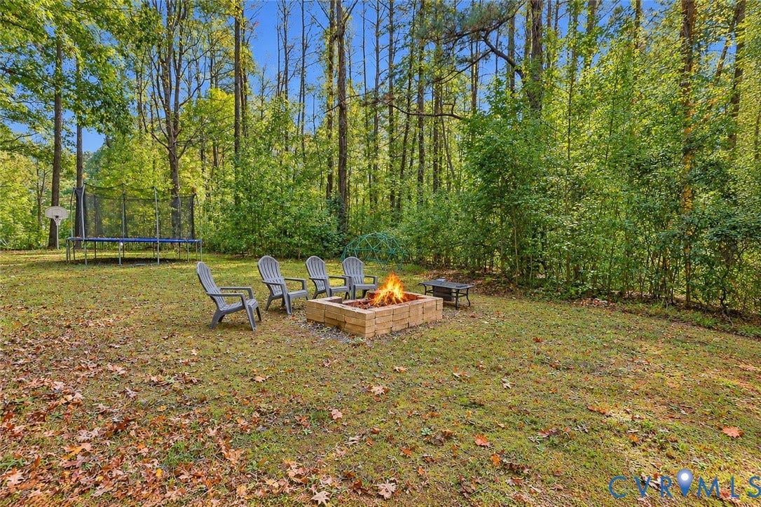 2764 Birdsong Lane, Powhatan, VA 23139 More front yard featuring a stone fire pit and a backdrop of dense mature trees