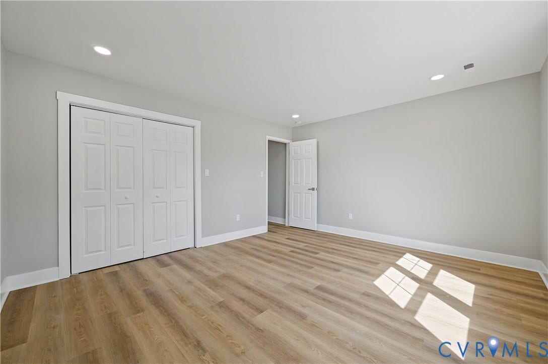 Neutral interior space featuring wood-finish flooring, recessed lighting, multi-panel doors, and a double-door closet