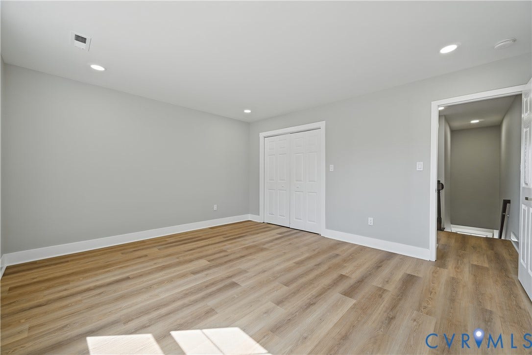 Neutral-toned interior featuring wood-finish flooring, recessed lighting, and double-door reach-in closet cabinetry