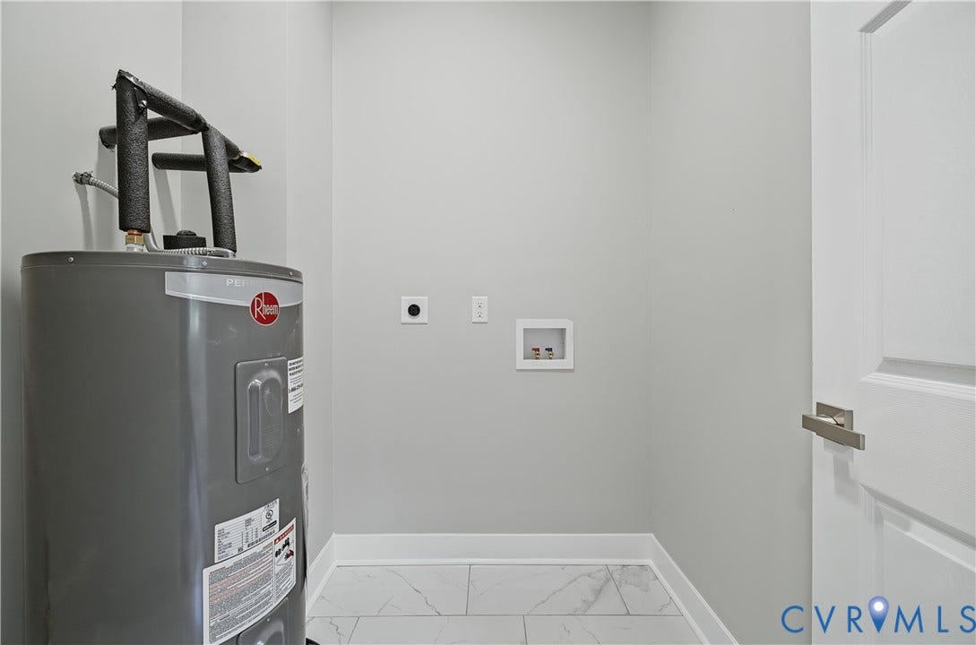 Utility area featuring a Rheem water heater, white recessed laundry hookups, and large-format tile flooring
