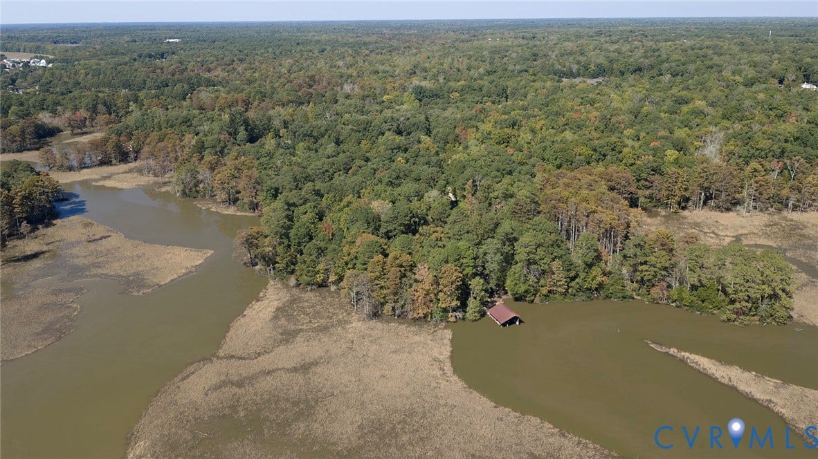 234 Sandy Bay Road, Williamsburg, VA 23185 Aerial perspective of waterfront acreage featuring extensive tree coverage, marshland shoreline, and a private covered boat slip