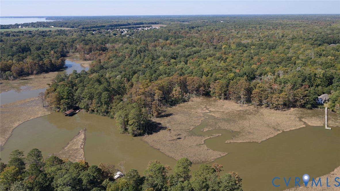 234 Sandy Bay Road, Williamsburg, VA 23185 Aerial perspective of waterfront acreage featuring wooded terrain, marshland, and a private dock