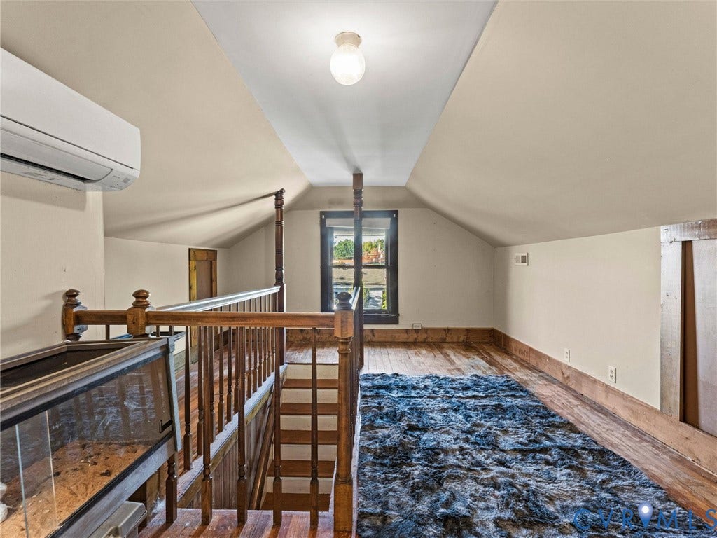 124 Suffolk Avenue, Chesterfield Highlands, Colonial Heights, VA 23834 Vaulted ceilings, wood flooring, wood spindle railing, wall-mounted heating and cooling unit, and natural light from a window with dark wood trim