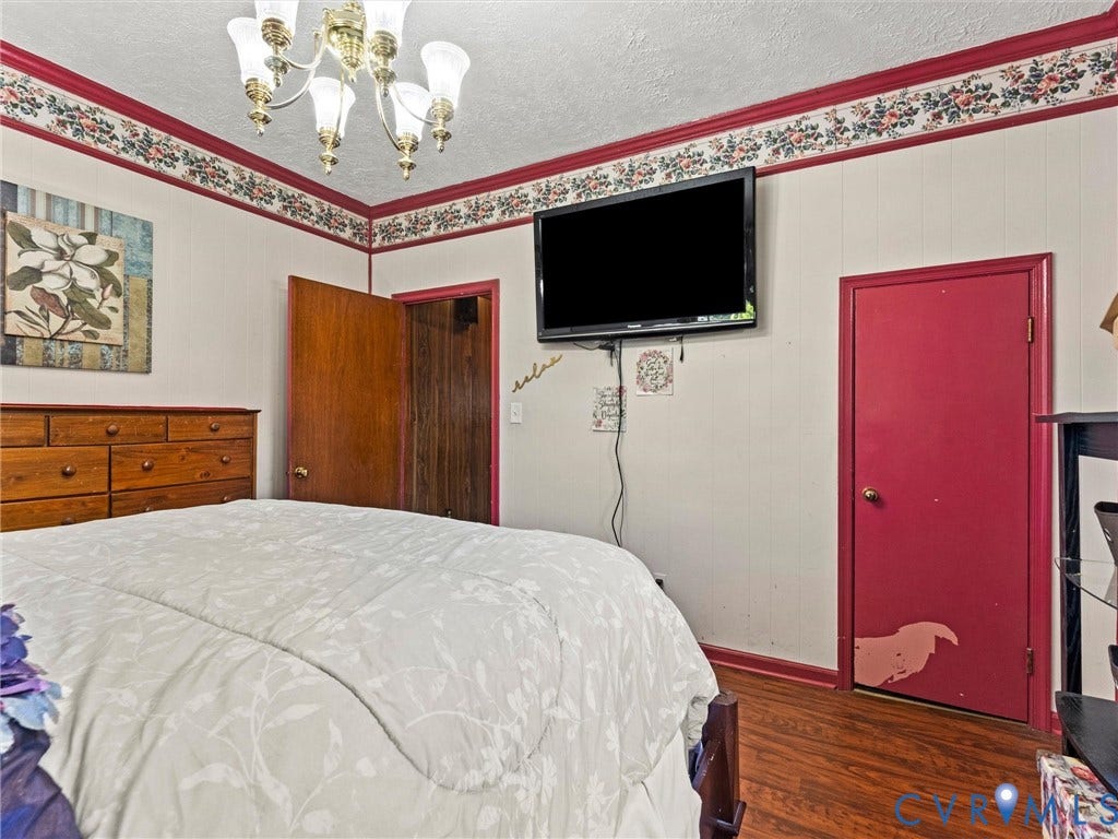 124 Suffolk Avenue, Chesterfield Highlands, Colonial Heights, VA 23834 Bedroom featuring wood-finish flooring, decorative floral wallpaper border, and a classic multi-arm chandelier