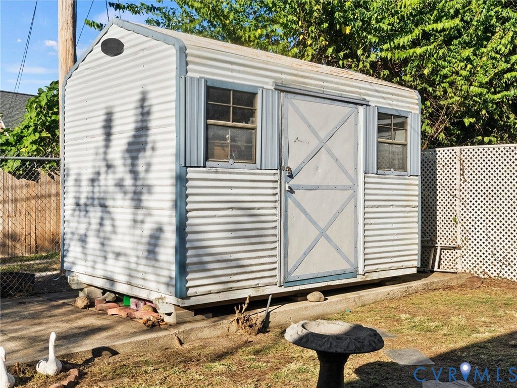 124 Suffolk Avenue, Chesterfield Highlands, Colonial Heights, VA 23834 Storage shed featuring corrugated metal siding, two multi-pane windows, and a reinforced door, set upon a concrete foundation