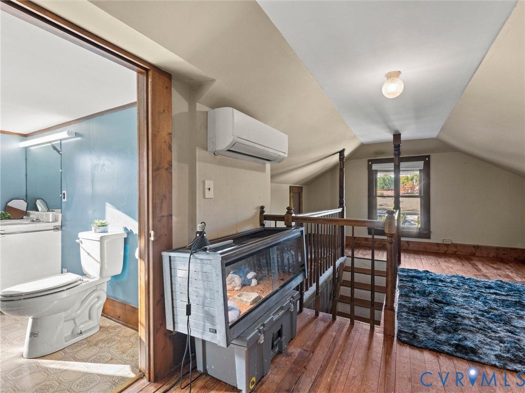 124 Suffolk Avenue, Chesterfield Highlands, Colonial Heights, VA 23834 Sloped ceiling interior featuring wood flooring, a wall-mounted ductless HVAC unit, and a wooden balustrade staircase railing