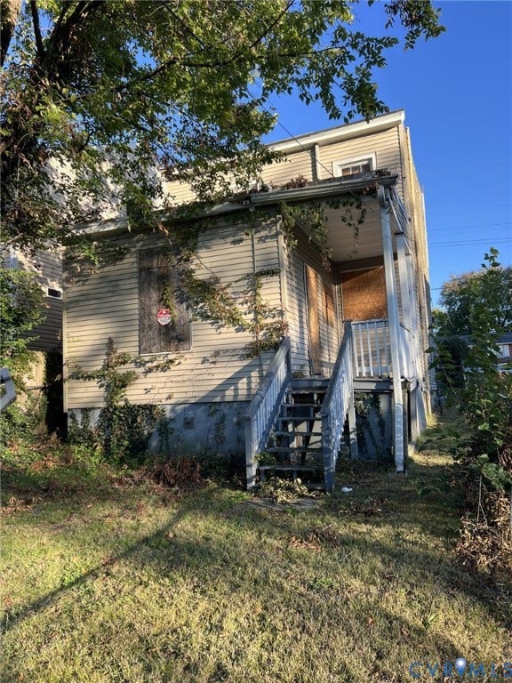 1512 N 23rd Street, Church Hill, Richmond, VA 23223 Two-story exterior featuring light-colored horizontal siding, a covered porch with wooden stairs, and a concrete foundation