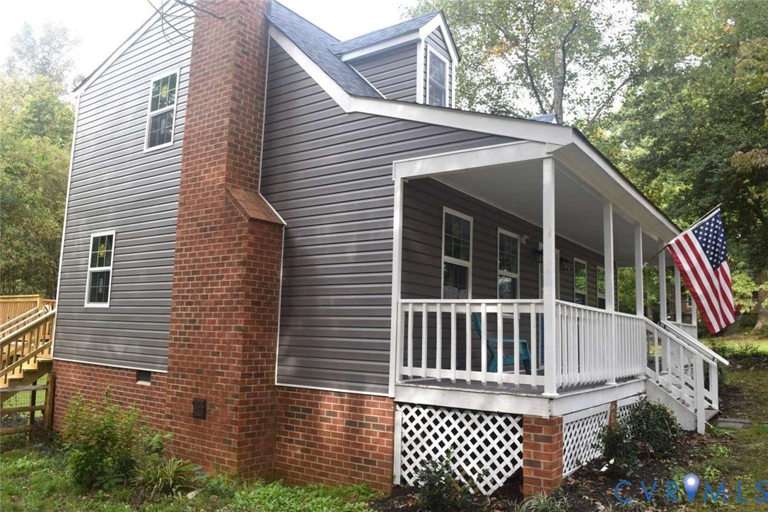 7300 Key Deer Court, Deer Run, Midlothian, VA 23112 Two-story exterior featuring dark horizontal siding, a classic brick chimney, a covered front porch with white railing, and decorative lattice skirting