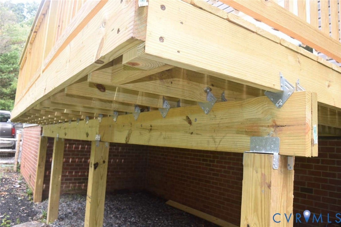 7300 Key Deer Court, Deer Run, Midlothian, VA 23112 Elevated wood deck featuring structural support posts, pressure-treated lumber joists, metal joist hangers, and a red brick foundation exterior