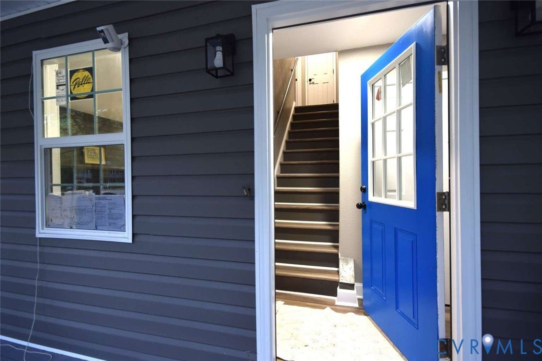 7300 Key Deer Court, Deer Run, Midlothian, VA 23112 Exterior featuring dark horizontal siding, a blue paneled door with a six-pane window insert, and a single-hung window with a grid pattern