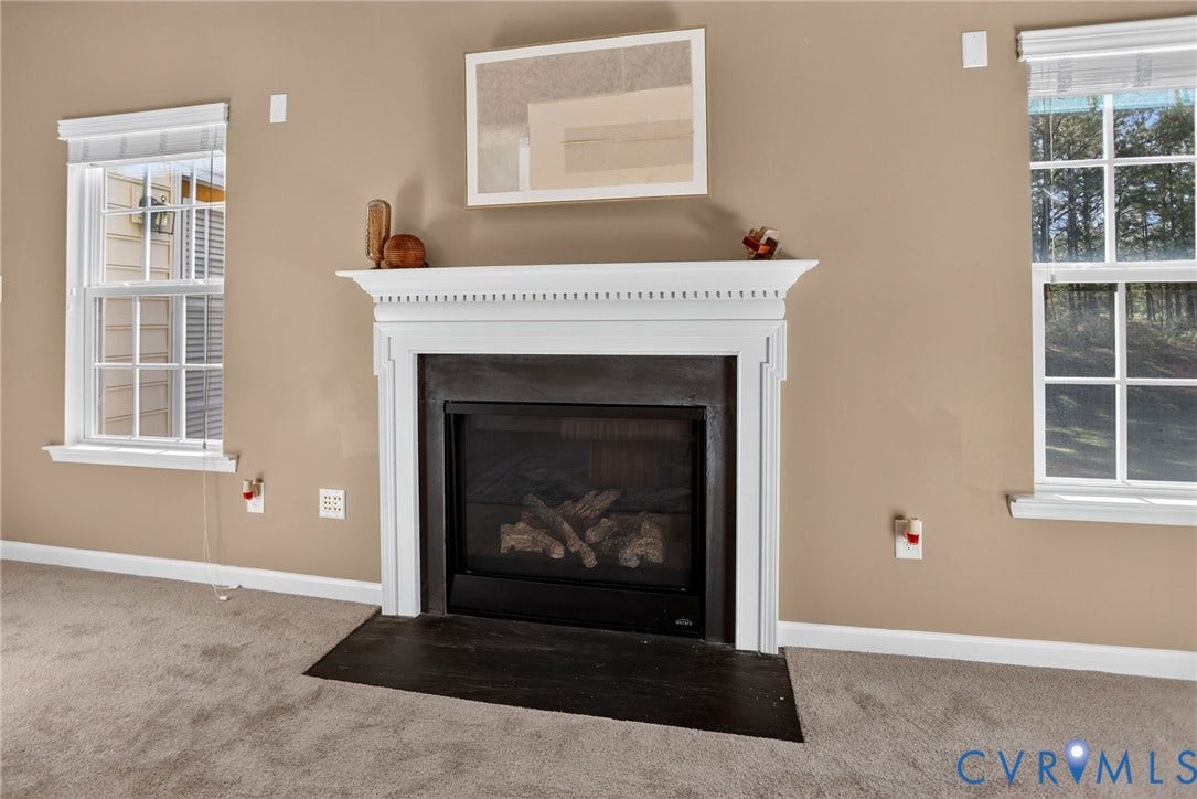 10851 White Dogwood Drive, Oakmont Villas, New Kent, VA 23140 Fireplace with a classic white decorative mantel, dark tile surround, and black hearth, framed by dual windows with integrated blinds