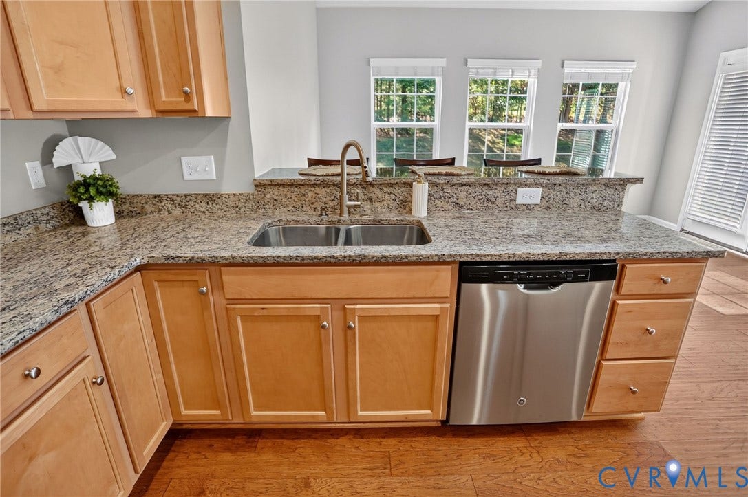 10851 White Dogwood Drive, Oakmont Villas, New Kent, VA 23140 Kitchen featuring natural wood cabinetry, stone-surface countertops, stainless steel dishwasher, double-basin undermount sink, and multi-pane windows