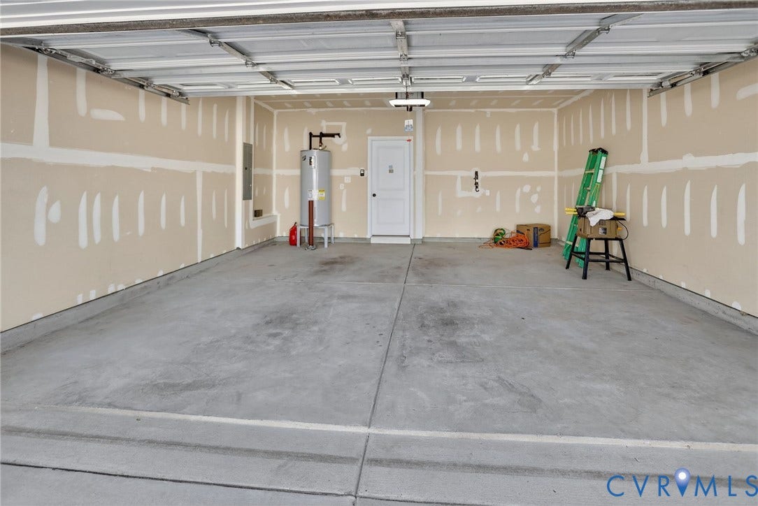 10851 White Dogwood Drive, Oakmont Villas, New Kent, VA 23140 Attached two-car garage featuring a concrete floor, sectional roll-up door, interior access door, and water heater