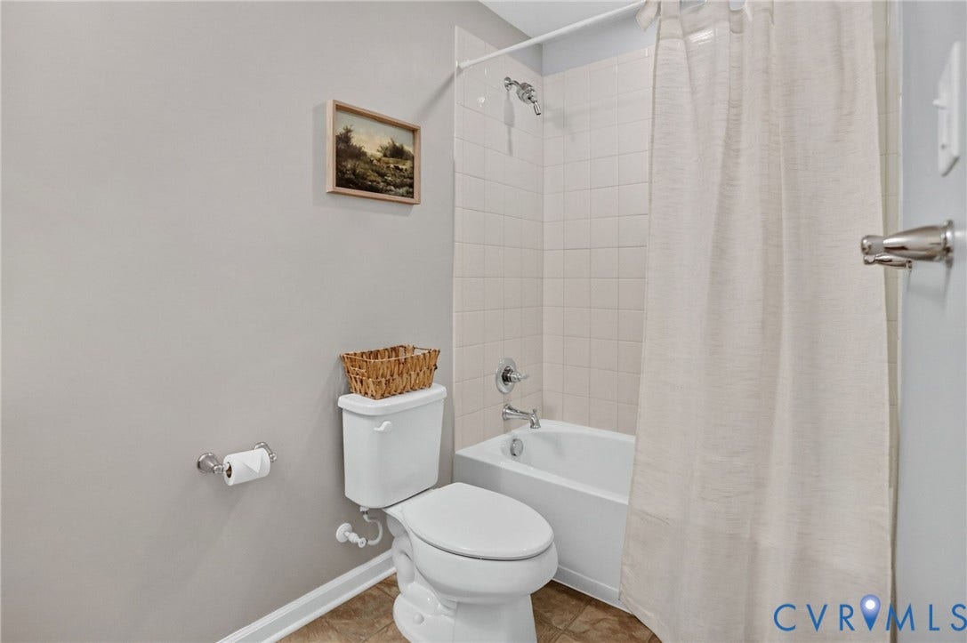 10851 White Dogwood Drive, Oakmont Villas, New Kent, VA 23140 Full bathroom featuring a white porcelain tub, ceramic tile wall surround, chrome shower fixtures, and a white elongated toilet