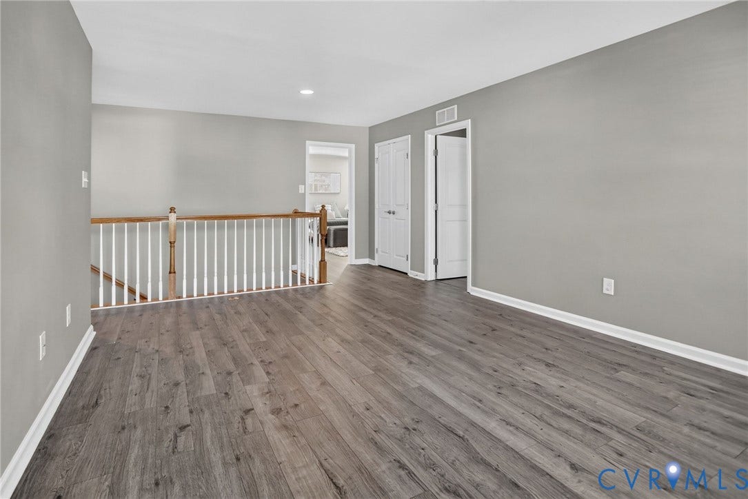 10851 White Dogwood Drive, Oakmont Villas, New Kent, VA 23140 Interior space featuring wood-finish flooring, neutral wall paint, and a staircase landing with a stained-wood railing and white balusters