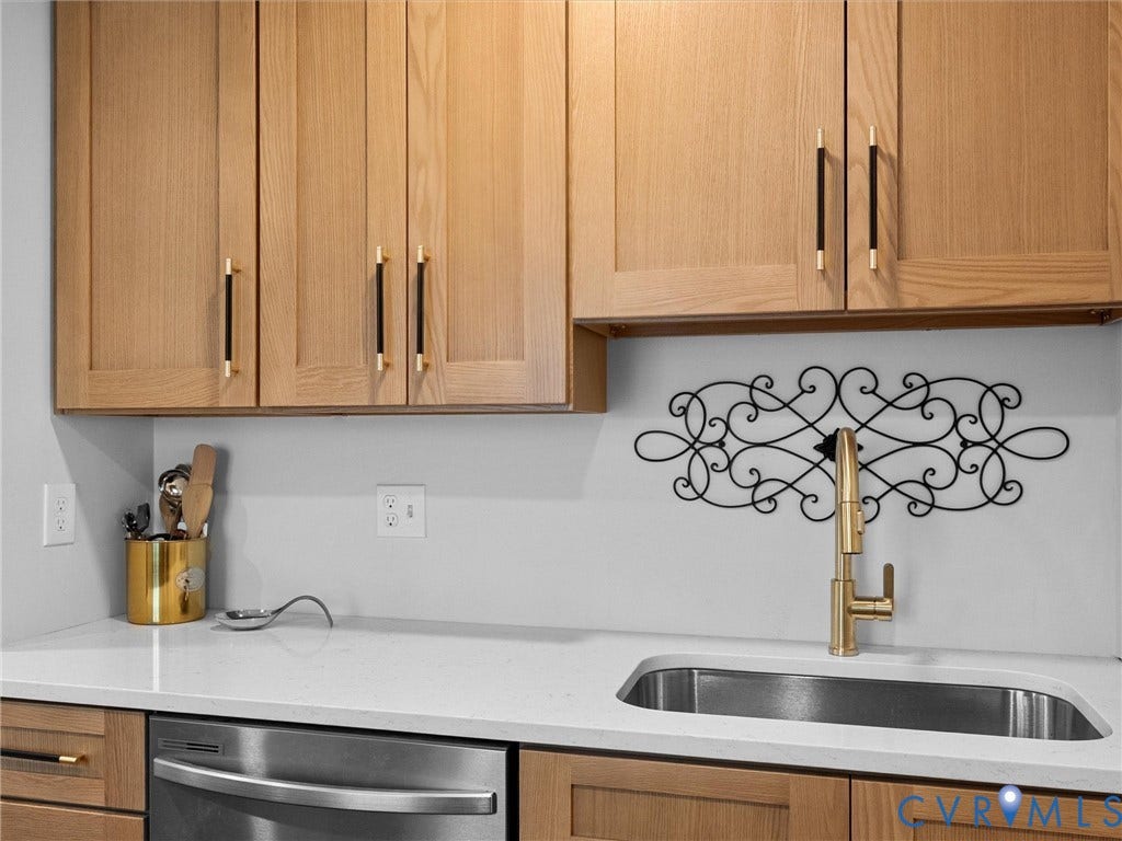1826 Claiborne Street, Byrd Park, Richmond, VA 23220 Flat-panel wood-finish cabinetry featuring black and gold bar pulls, solid-surface countertop, undermount stainless steel sink, and high-arch gold-finish faucet