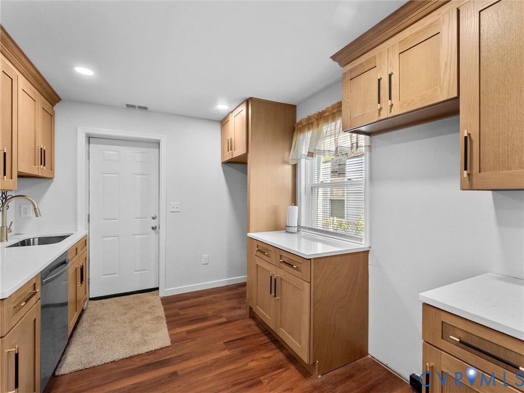 1826 Claiborne Street, Byrd Park, Richmond, VA 23220 Light wood cabinetry featuring matte black hardware, white solid-surface countertops, wood-finish flooring, and a stainless steel undermount sink