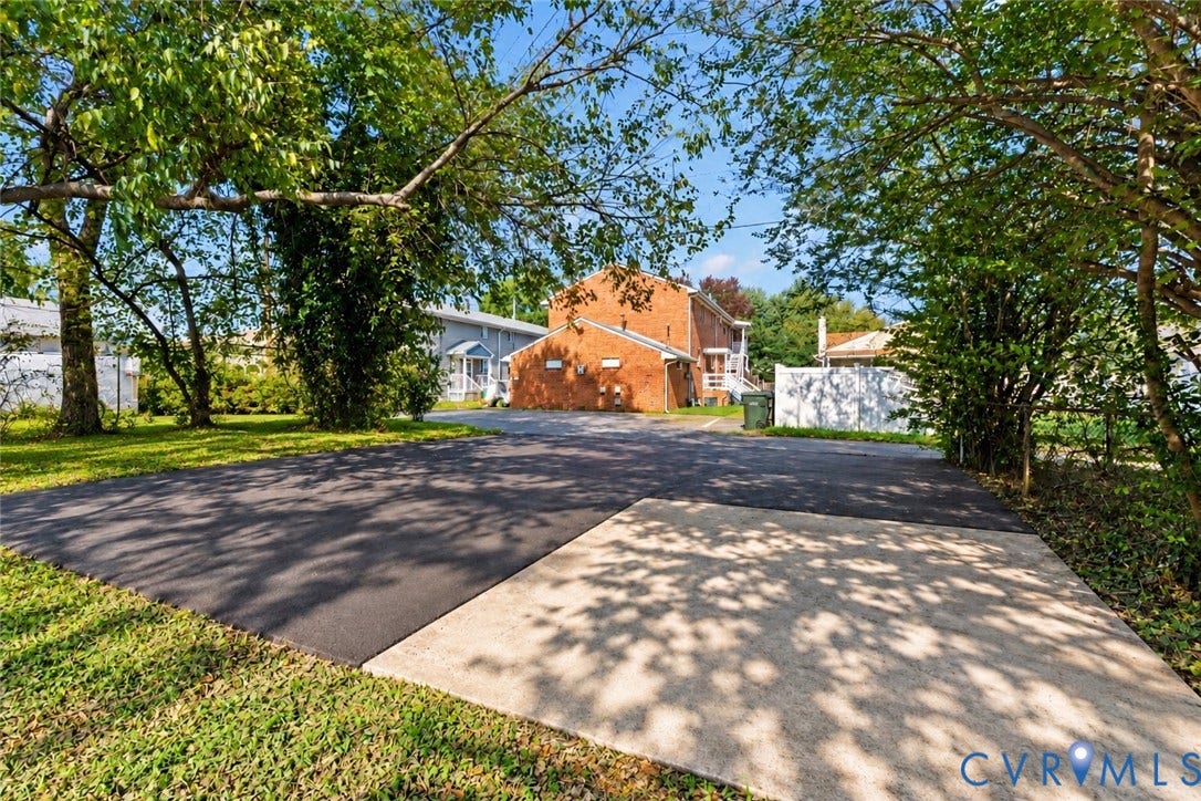 1826 Claiborne Street, Byrd Park, Richmond, VA 23220 Paved off-street parking area with asphalt and concrete surfaces, surrounded by mature trees and a privacy fence