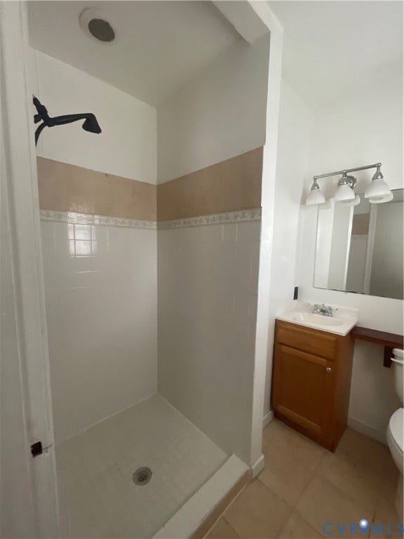 1214 N 30th Street, Richmond, VA 23223 Walk-in shower with tile surround, wood-finish vanity with integrated sink, three-light fixture, and ceramic tile flooring
