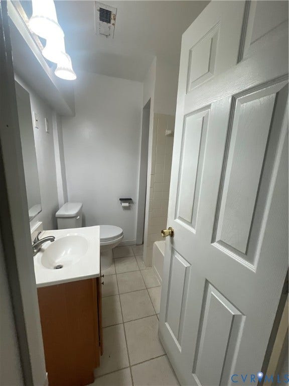 1214 N 30th Street, Richmond, VA 23223 Bathroom featuring a vanity with a white countertop and oval basin, tile flooring, wall-mounted light fixture, and a white six-panel door