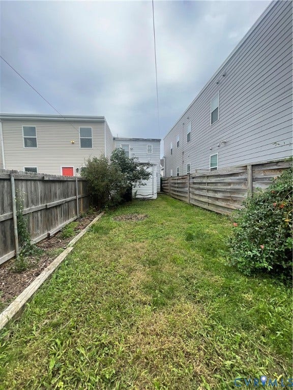 1214 N 30th Street, Richmond, VA 23223 Fenced backyard featuring a manicured lawn, established landscaping, and timber border edging