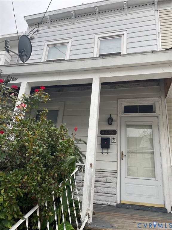 1214 N 30th Street, Richmond, VA 23223 Exterior facade featuring horizontal siding, a covered front porch with decorative iron railings, stone masonry accents, and a transom window above the entry door
