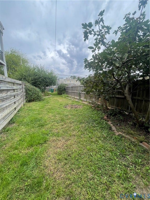 1214 N 30th Street, Richmond, VA 23223 Rear yard featuring a grass lawn, horizontal wood fencing, and mature trees