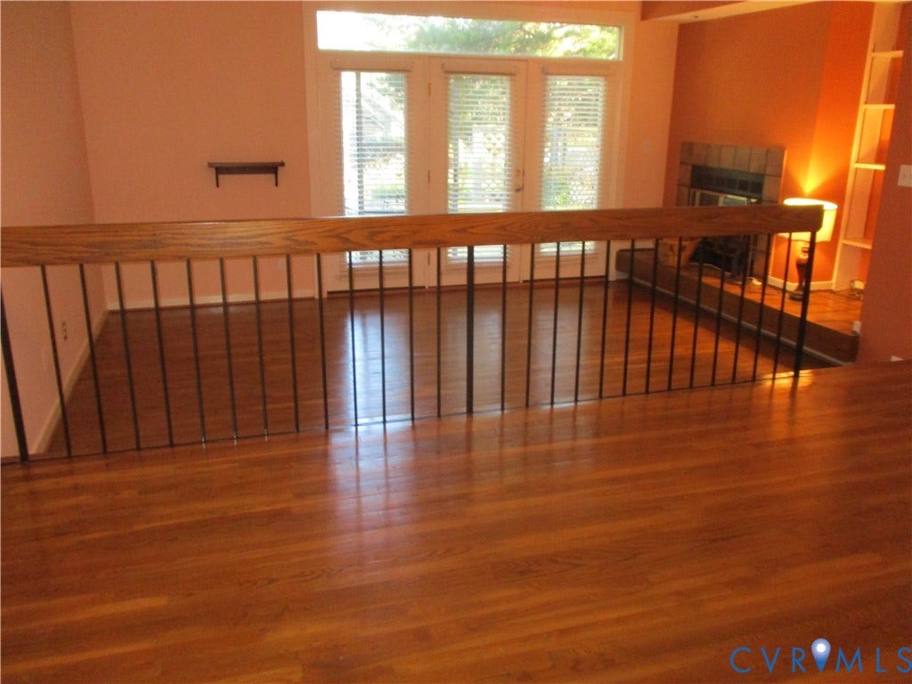12400 New Point Drive, Wilde Lake, Henrico, VA 23233 Wood-finish flooring, fireplace with a tiled surround, built-in shelving, wood-capped metal handrail, and glass-paneled double doors