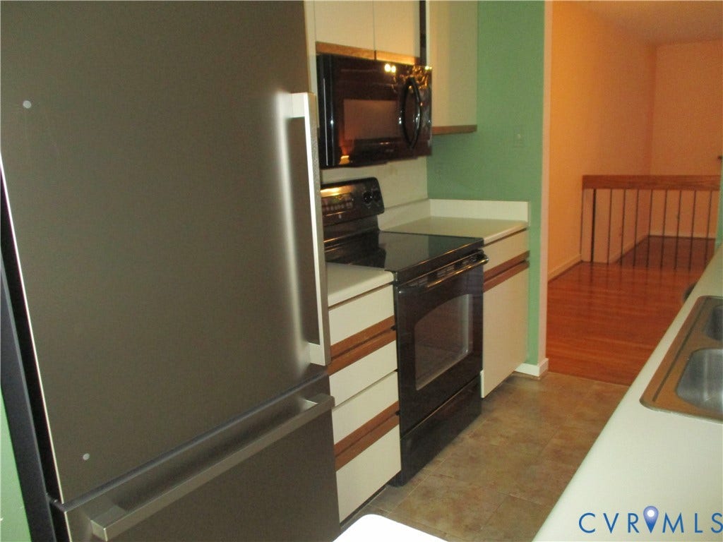 12400 New Point Drive, Wilde Lake, Henrico, VA 23233 Kitchen featuring a stainless steel refrigerator, black appliance suite, solid-surface countertops, flat-panel cabinetry, and dual-basin sink