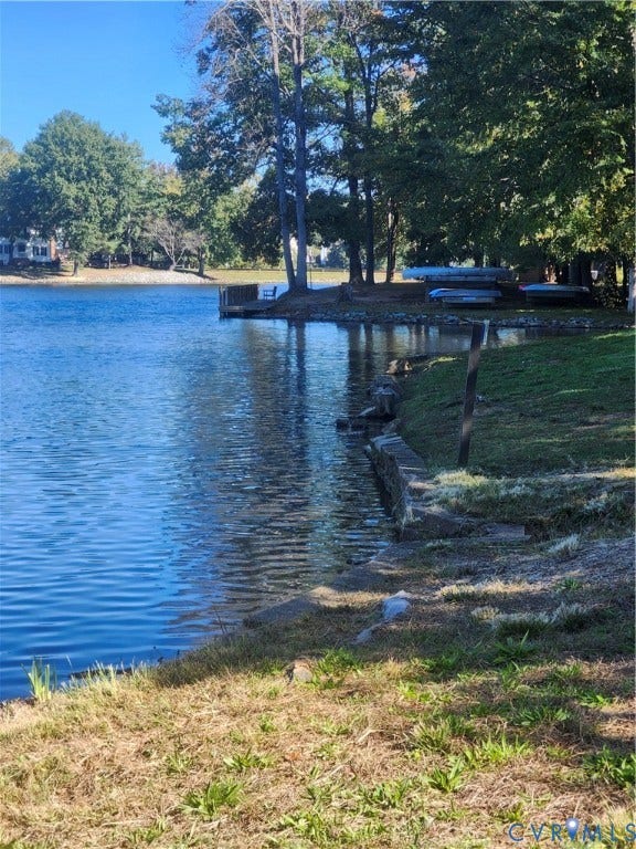 12400 New Point Drive, Wilde Lake, Henrico, VA 23233 Waterfront property featuring a stone bulkhead, wooden dock, mature trees, and expansive shoreline