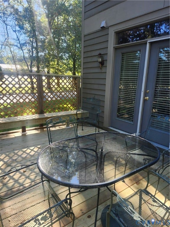 12400 New Point Drive, Wilde Lake, Henrico, VA 23233 Wood-deck patio featuring a built-in lattice privacy screen, horizontal lap siding, and double glass-panel entry doors with wall-mounted exterior lighting
