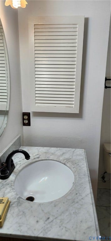 12400 New Point Drive, Wilde Lake, Henrico, VA 23233 Stone-topped vanity featuring an undermount oval sink, matte black faucet, and louvered wall-mounted storage cabinet