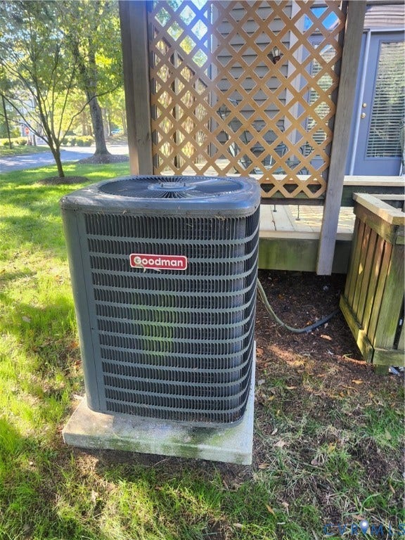 12400 New Point Drive, Wilde Lake, Henrico, VA 23233 Exterior Goodman condenser unit mounted on a concrete pad, situated near a wood lattice privacy screen and vertical-plank enclosure