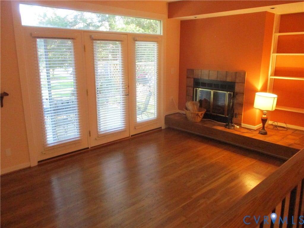 12400 New Point Drive, Wilde Lake, Henrico, VA 23233 Wood-finish flooring, fireplace with tiled hearth, built-in shelving, and floor-to-ceiling glass panel doors
