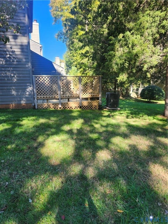 12400 New Point Drive, Wilde Lake, Henrico, VA 23233 Exterior rear wood deck featuring lattice privacy screening, siding, and an expansive lawn with mature trees
