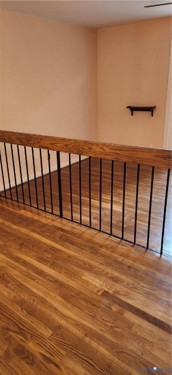 12400 New Point Drive, Wilde Lake, Henrico, VA 23233 Wood-finish flooring with a natural grain texture, featuring a wooden handrail supported by vertical metal balusters and a wall-mounted display shelf