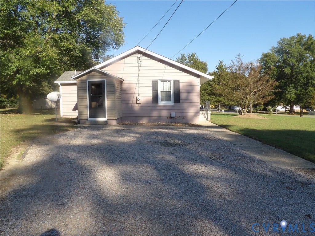 3206 South Street, Chester, VA 23831 Single-story residence featuring light-toned horizontal siding, a gabled roofline, dark-framed shutters, and an expansive gravel driveway