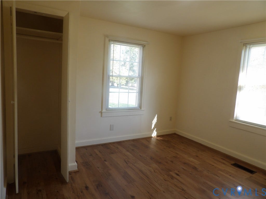 3206 South Street, Chester, VA 23831 Room featuring wood-finish flooring, two windows with grid muntins, and a built-in closet with overhead shelving