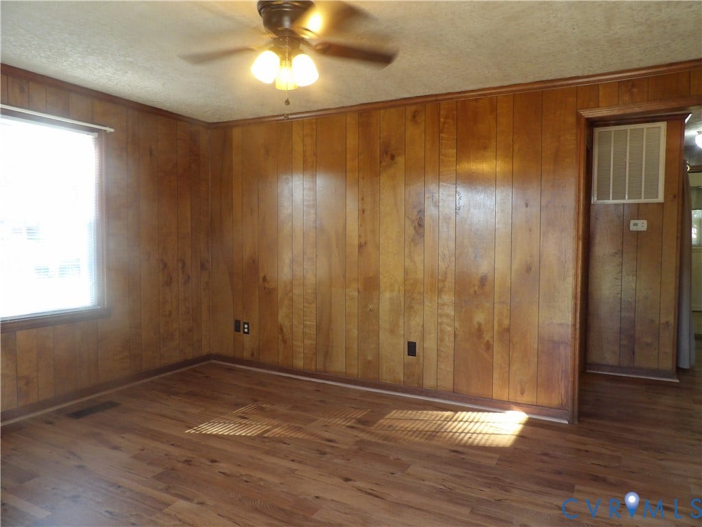3206 South Street, Chester, VA 23831 Interior space featuring wood-paneled walls, wood-finish flooring, and a ceiling-mounted light fixture with a central fan
