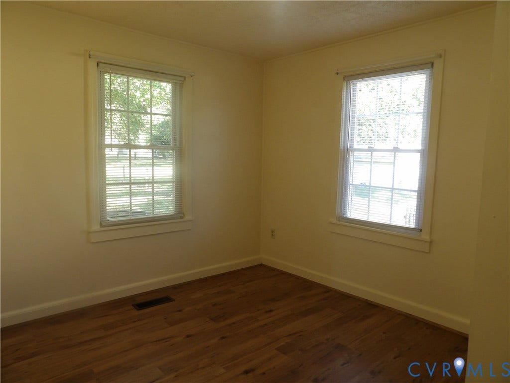 3206 South Street, Chester, VA 23831 Room featuring wood-finish flooring, neutral wall paint, and two double-hung windows with exterior casing