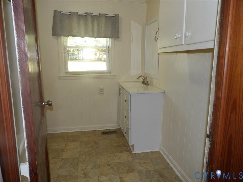 3206 South Street, Chester, VA 23831 Single-basin vanity with white cabinetry, square-tiled flooring, wall-mounted upper storage, and a multi-pane window